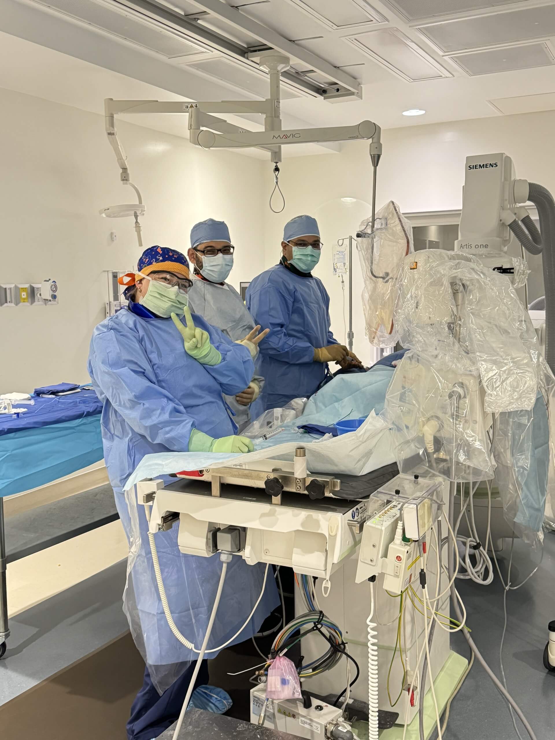 Medical team in surgical attire performing a procedure in a hospital operating room
